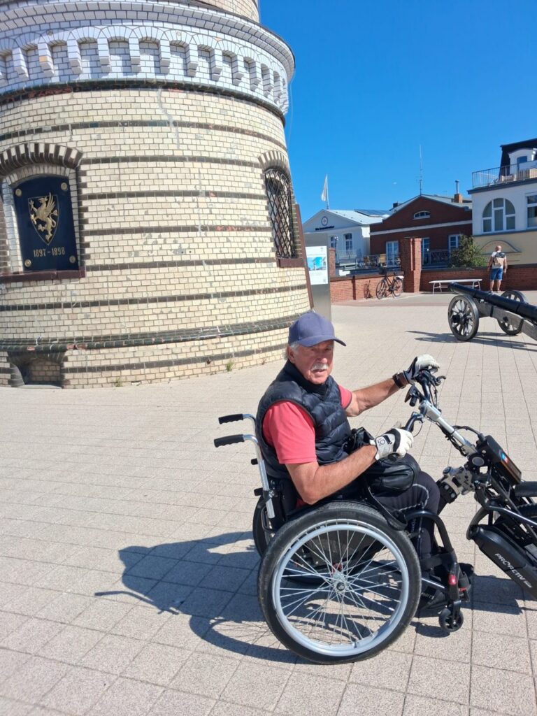 Wolfgang Steffan mit Handbike vor einem Leuchtturm an der Ostsee